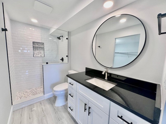 bathroom with tiled shower, vanity, toilet, and hardwood / wood-style floors