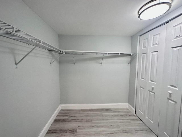 walk in closet with light wood-type flooring