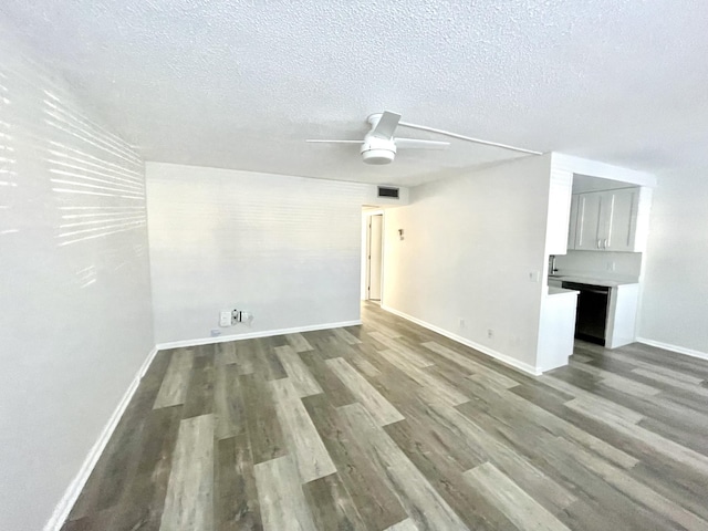 spare room featuring ceiling fan, dark hardwood / wood-style flooring, and a textured ceiling