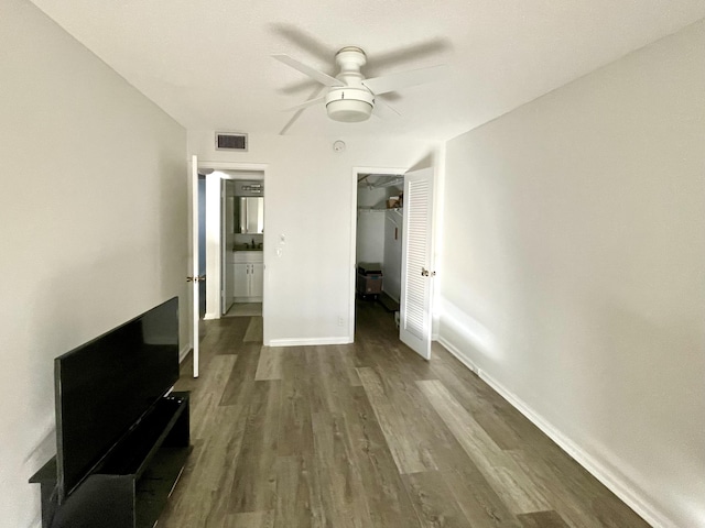 unfurnished bedroom featuring ceiling fan, a closet, dark wood-type flooring, and a spacious closet