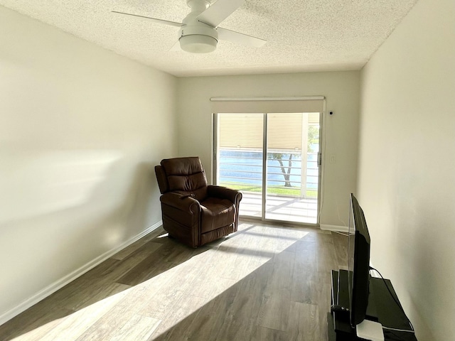 sitting room featuring ceiling fan, dark hardwood / wood-style floors, and a textured ceiling