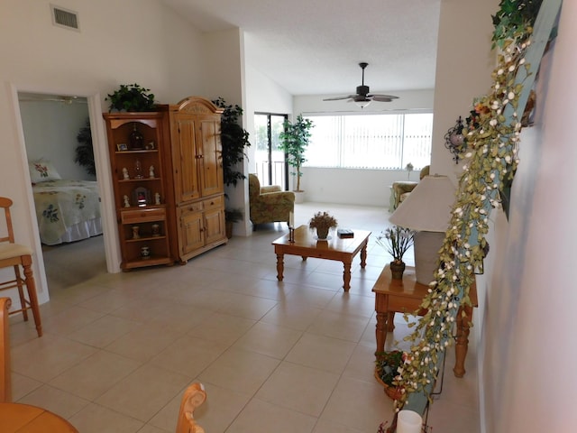 living room with ceiling fan, vaulted ceiling, and light tile patterned flooring