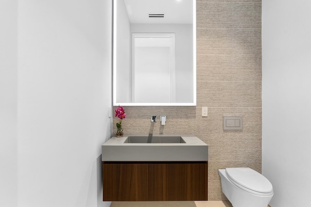 bathroom featuring vanity, toilet, and tile walls