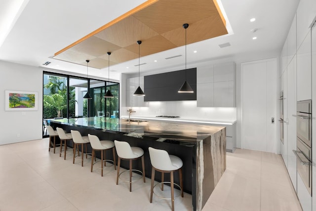 kitchen with a kitchen breakfast bar, a large island, white cabinets, and hanging light fixtures