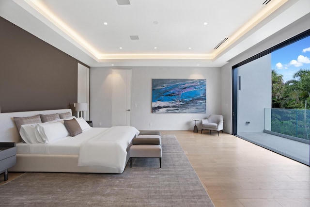 bedroom with a raised ceiling and light wood-type flooring