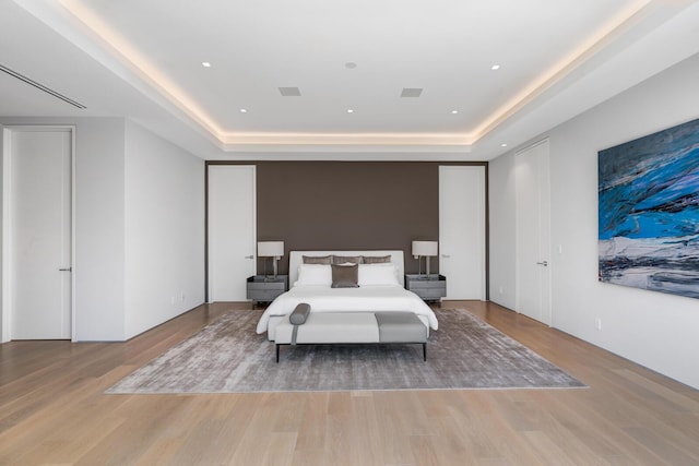 bedroom with a raised ceiling and light hardwood / wood-style flooring