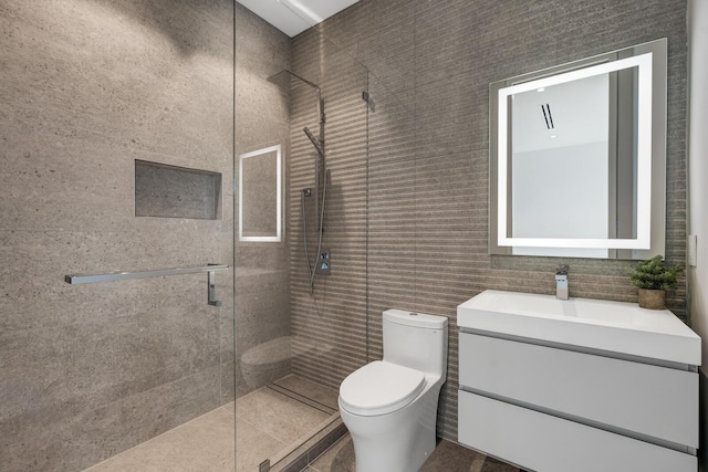 bathroom with tile patterned floors, walk in shower, vanity, tile walls, and toilet