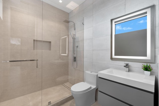 bathroom featuring vanity, toilet, tiled shower, and tile walls