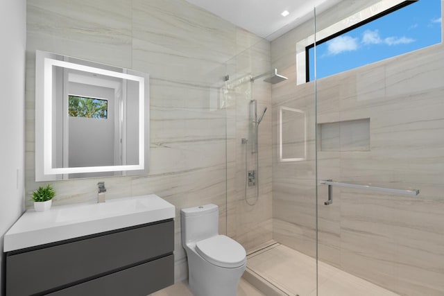 bathroom featuring walk in shower, vanity, plenty of natural light, and tile walls