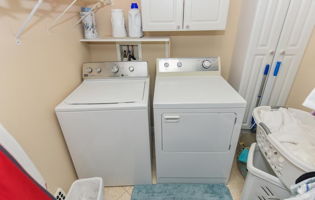 washroom with cabinets, light tile patterned flooring, and washing machine and clothes dryer