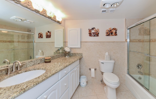 full bathroom featuring toilet, enclosed tub / shower combo, tile patterned flooring, tile walls, and vanity