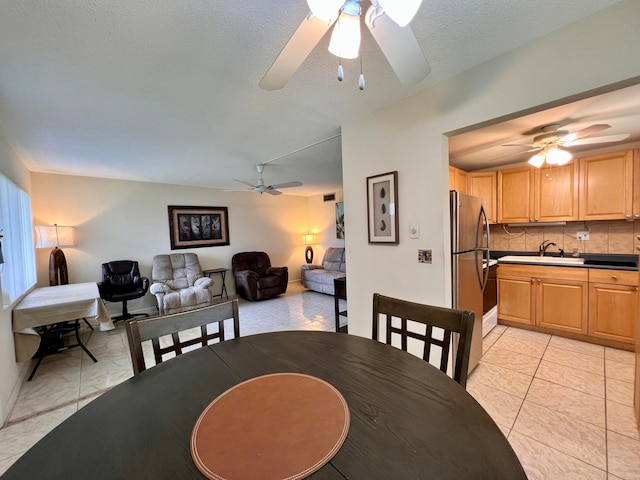 dining space featuring light tile patterned floors, sink, ceiling fan, and a textured ceiling