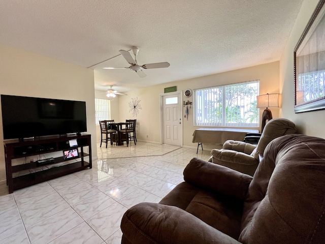 living area with baseboards, ceiling fan, a textured ceiling, and marble finish floor