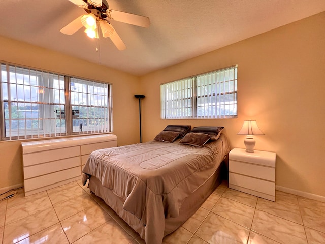 tiled bedroom with ceiling fan and multiple windows