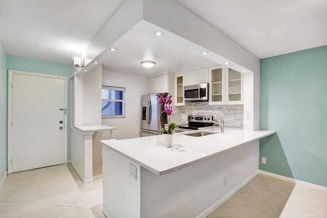 kitchen with white cabinets, kitchen peninsula, tasteful backsplash, and stainless steel appliances