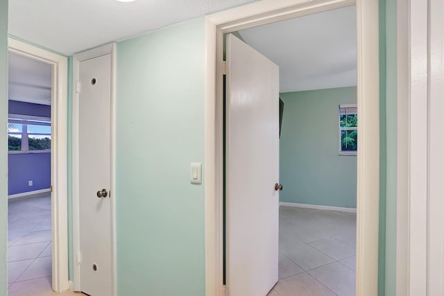 hallway with light tile patterned floors and a textured ceiling