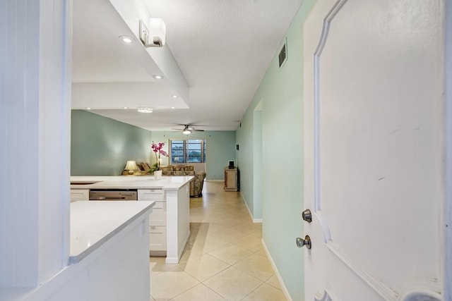 kitchen featuring kitchen peninsula, stainless steel dishwasher, ceiling fan, light tile patterned floors, and white cabinetry