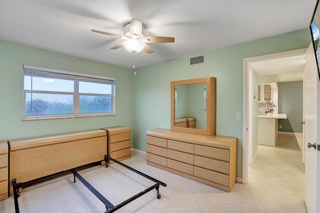 tiled bedroom featuring a textured ceiling, ceiling fan, and ensuite bathroom