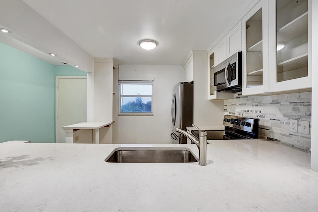 kitchen featuring backsplash, white cabinets, sink, light stone counters, and stainless steel appliances