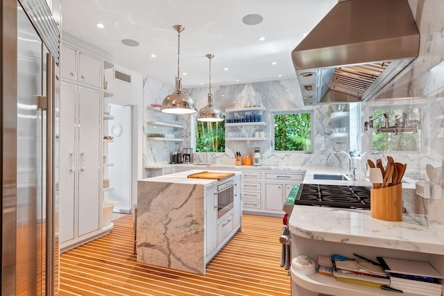 kitchen with tasteful backsplash, extractor fan, light wood-type flooring, sink, and white cabinets