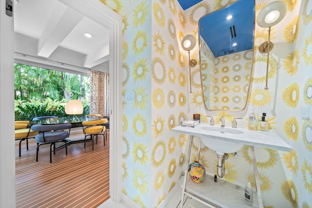 bathroom with sink, wood-type flooring, and beamed ceiling