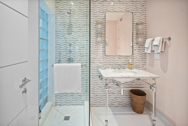 bathroom featuring sink, backsplash, and a shower with door