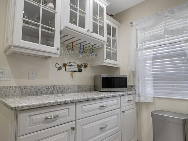 kitchen with white cabinetry and light stone counters