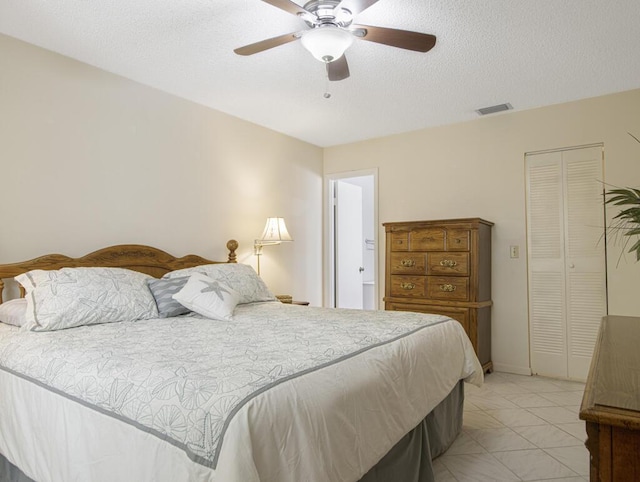 tiled bedroom with ceiling fan, a closet, and a textured ceiling