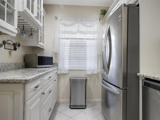 kitchen featuring white cabinets, light stone counters, light tile patterned floors, and appliances with stainless steel finishes