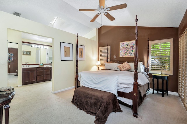 bedroom featuring connected bathroom, vaulted ceiling, light carpet, ceiling fan, and sink