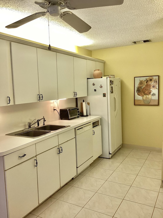 kitchen with a textured ceiling, sink, light tile patterned flooring, and white appliances