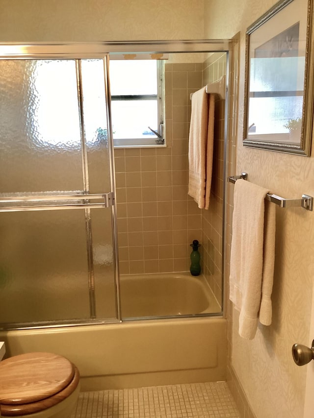 bathroom with tile patterned flooring, toilet, and shower / bath combination with glass door