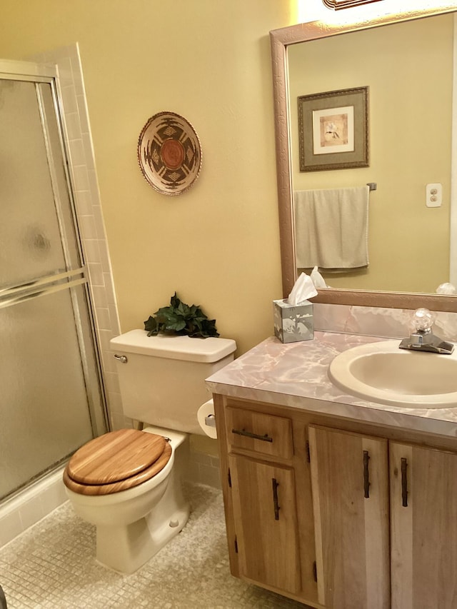 bathroom featuring tile patterned floors, a shower with door, vanity, and toilet