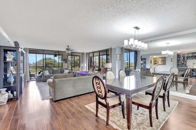 dining area with ceiling fan with notable chandelier, a textured ceiling, dark hardwood / wood-style flooring, and a wealth of natural light