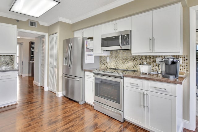 kitchen with white cabinetry, tasteful backsplash, ornamental molding, appliances with stainless steel finishes, and dark wood-type flooring