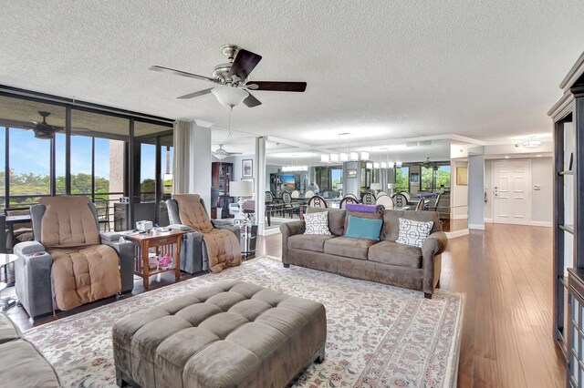 living room with a textured ceiling, ceiling fan, and wood-type flooring