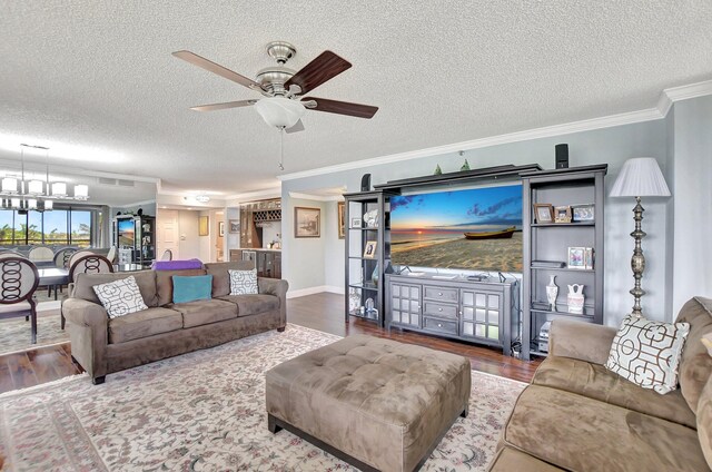 living room with hardwood / wood-style flooring, ceiling fan with notable chandelier, crown molding, and a textured ceiling