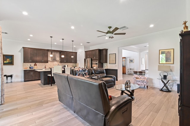 living room with ceiling fan, ornamental molding, and light hardwood / wood-style flooring