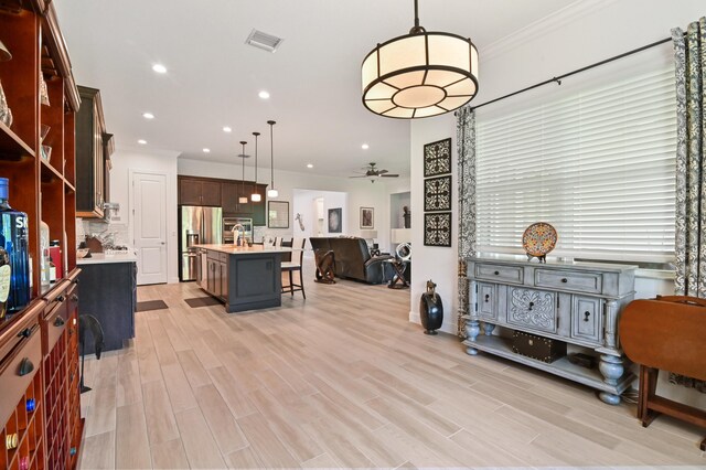 interior space featuring crown molding, ceiling fan, sink, and light hardwood / wood-style flooring