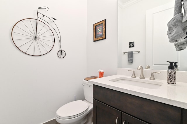 bathroom with ornamental molding, vanity, and toilet