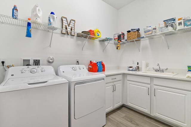 laundry room with cabinets, separate washer and dryer, sink, and light wood-type flooring