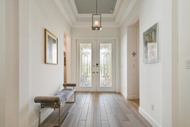 entryway featuring french doors, ornamental molding, wood-type flooring, and a tray ceiling