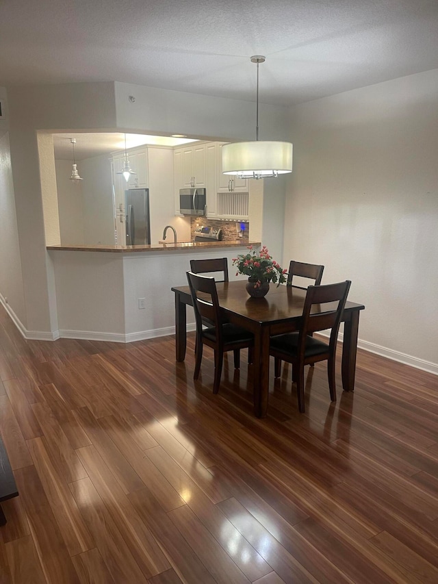 dining space with sink, a textured ceiling, and dark hardwood / wood-style flooring