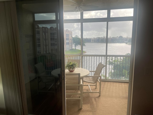 sunroom with a water view and ceiling fan