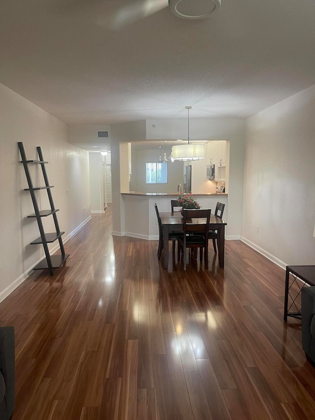 dining area with a notable chandelier and dark hardwood / wood-style flooring