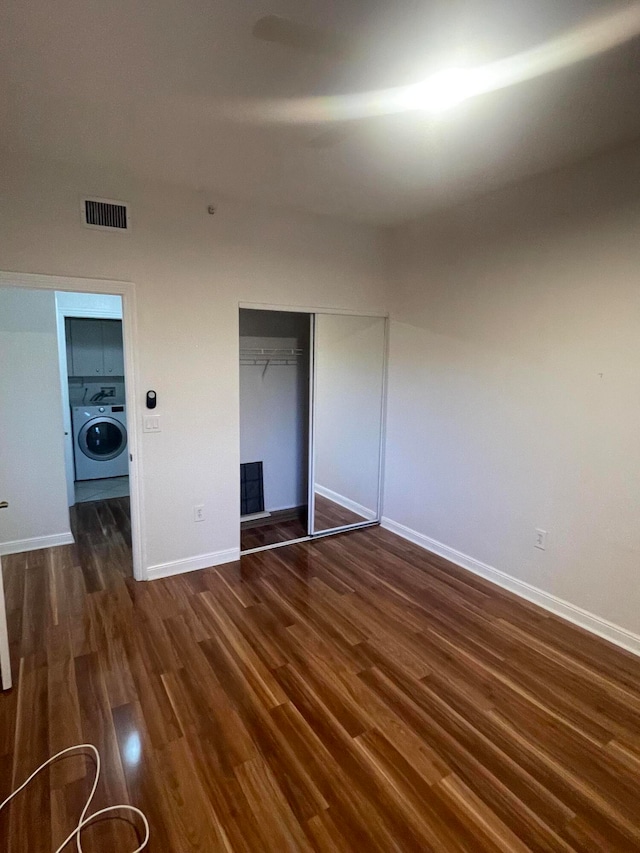 unfurnished bedroom with a closet, dark wood-type flooring, and washer / clothes dryer