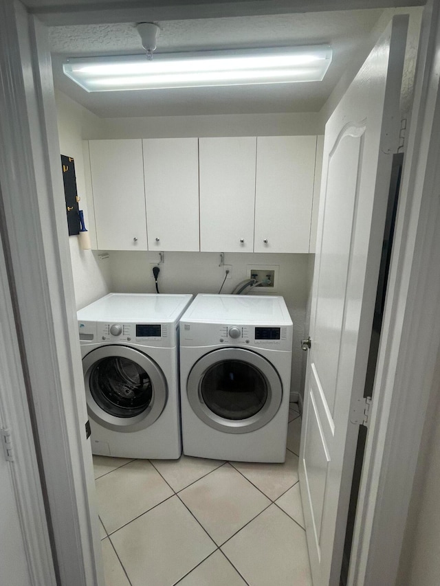 clothes washing area with light tile patterned flooring, separate washer and dryer, and cabinets