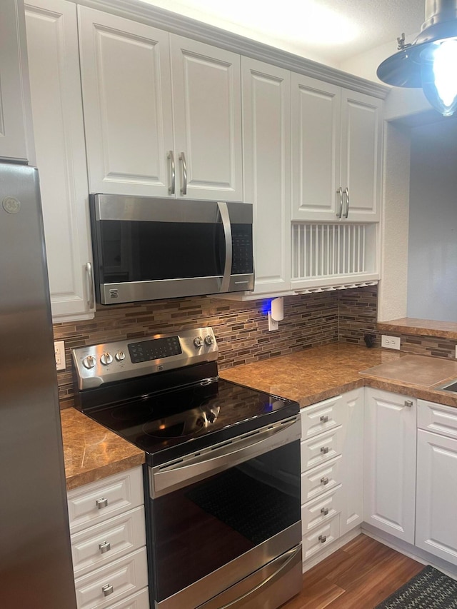 kitchen featuring decorative backsplash, white cabinetry, stainless steel appliances, and wood-type flooring