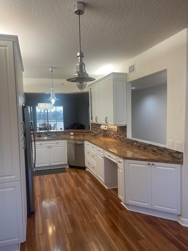 kitchen with kitchen peninsula, stainless steel appliances, pendant lighting, white cabinets, and dark wood-type flooring