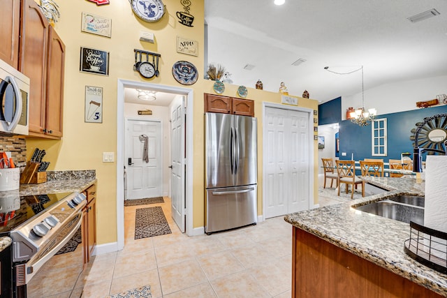 kitchen with light tile flooring, pendant lighting, a notable chandelier, light stone counters, and appliances with stainless steel finishes